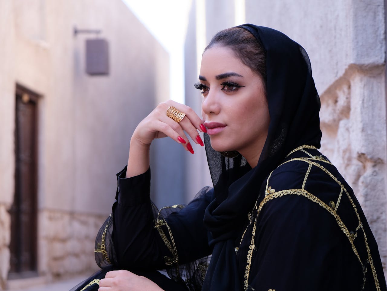 Elegant Middle Eastern woman in traditional fashion, sitting outdoors in Dubai.